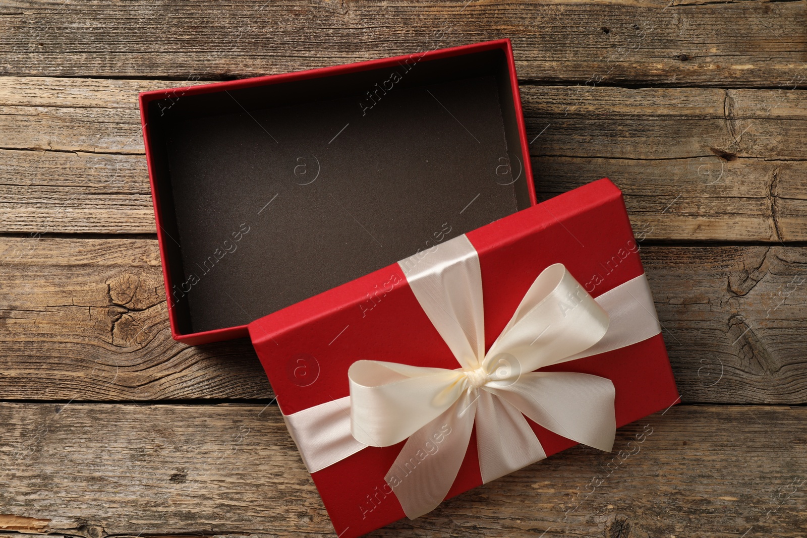 Photo of Opened gift box with beautiful lid on wooden table, top view