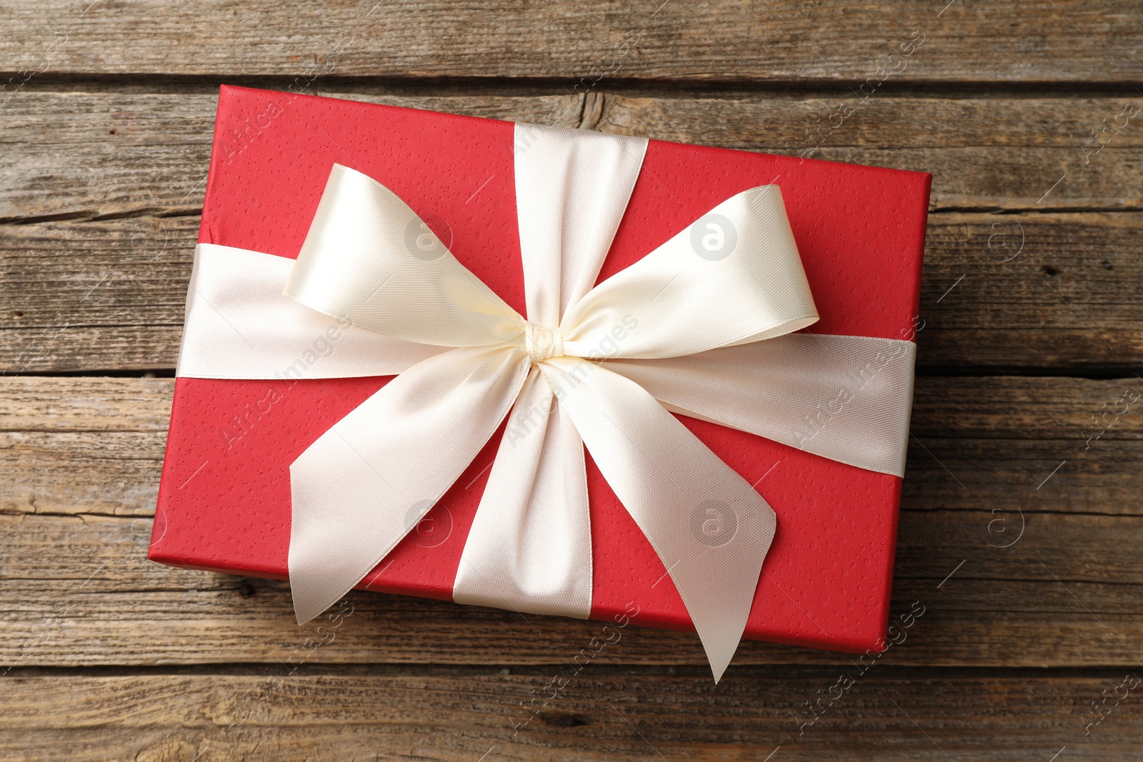 Photo of Gift box with beautiful bow on wooden table, top view