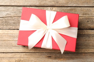 Photo of Gift box with beautiful bow on wooden table, top view