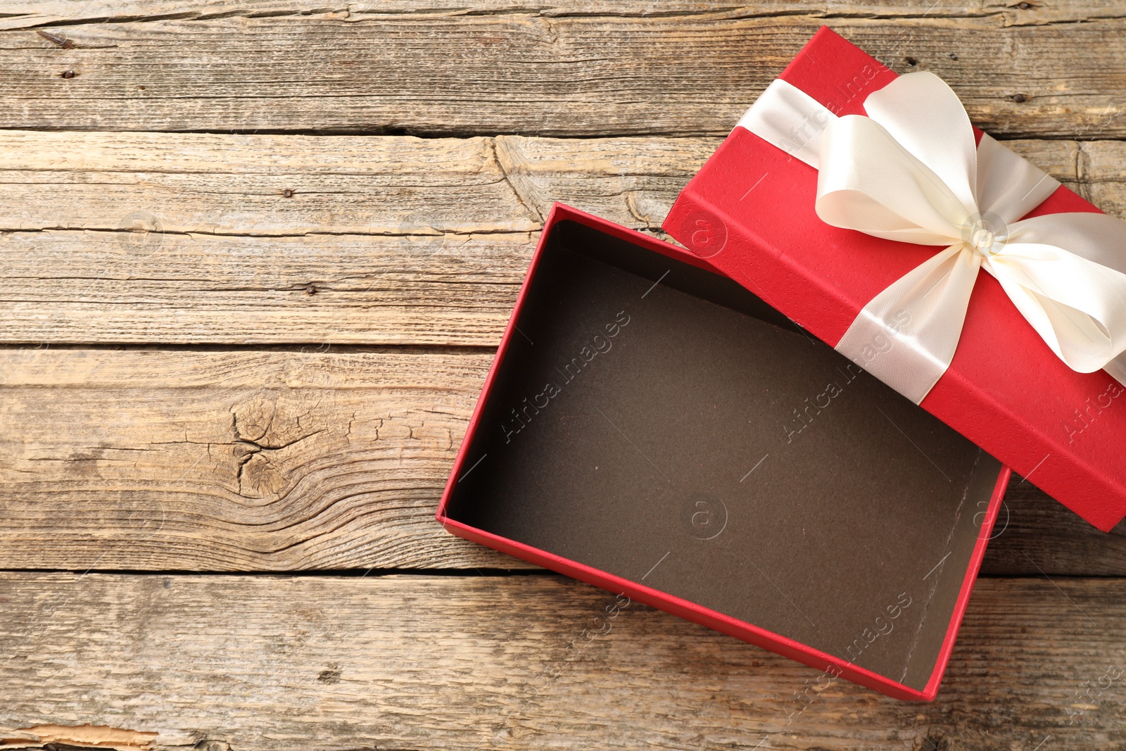 Photo of Opened gift box with beautiful lid on wooden table, top view. Space for text