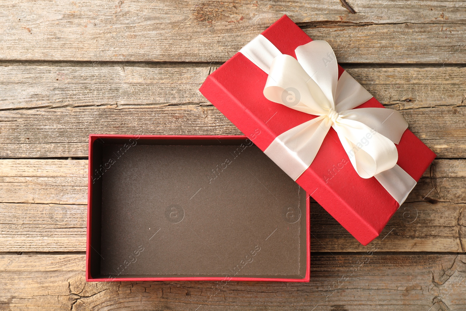 Photo of Opened gift box with beautiful lid on wooden table, top view