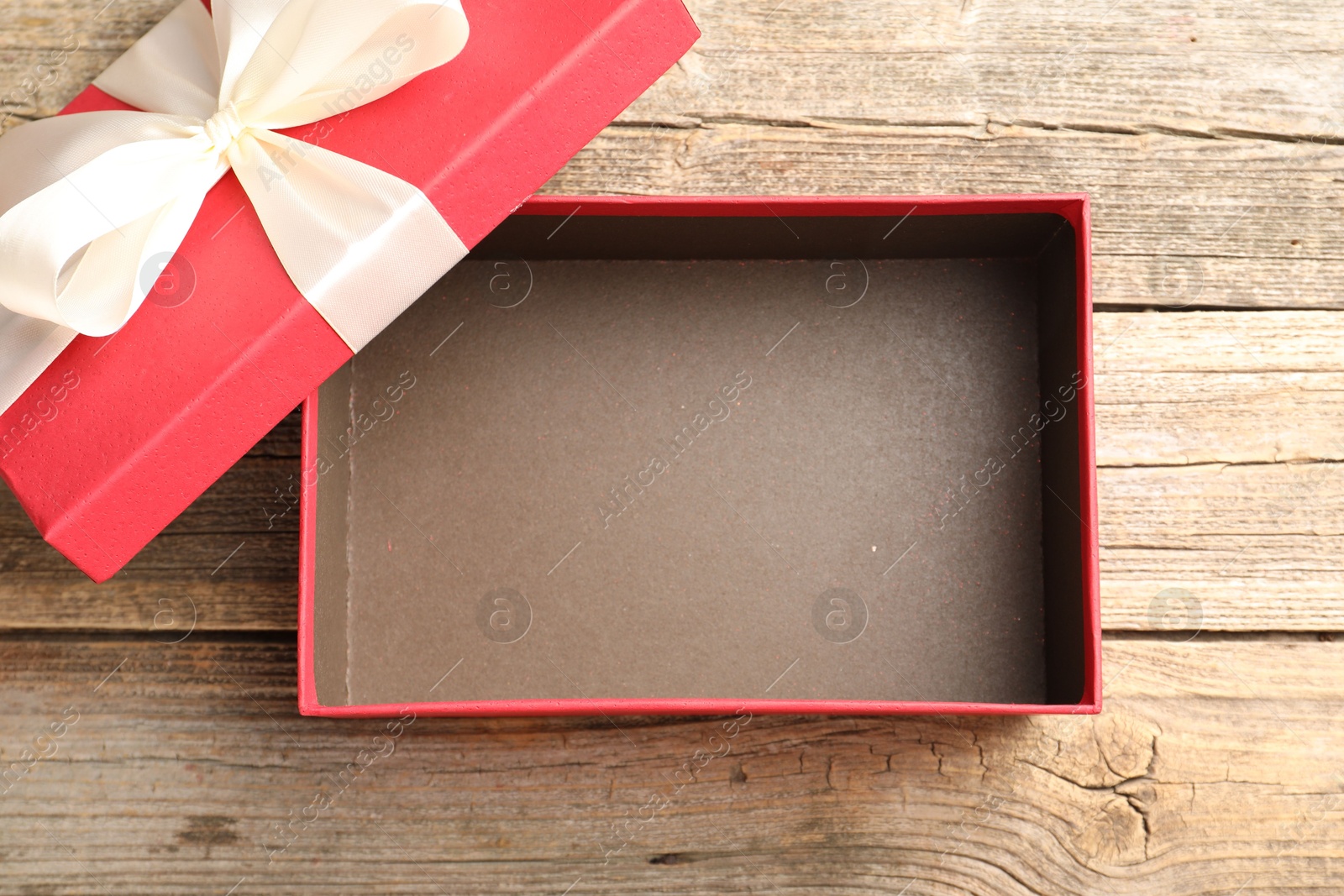 Photo of Opened gift box with beautiful lid on wooden table, top view