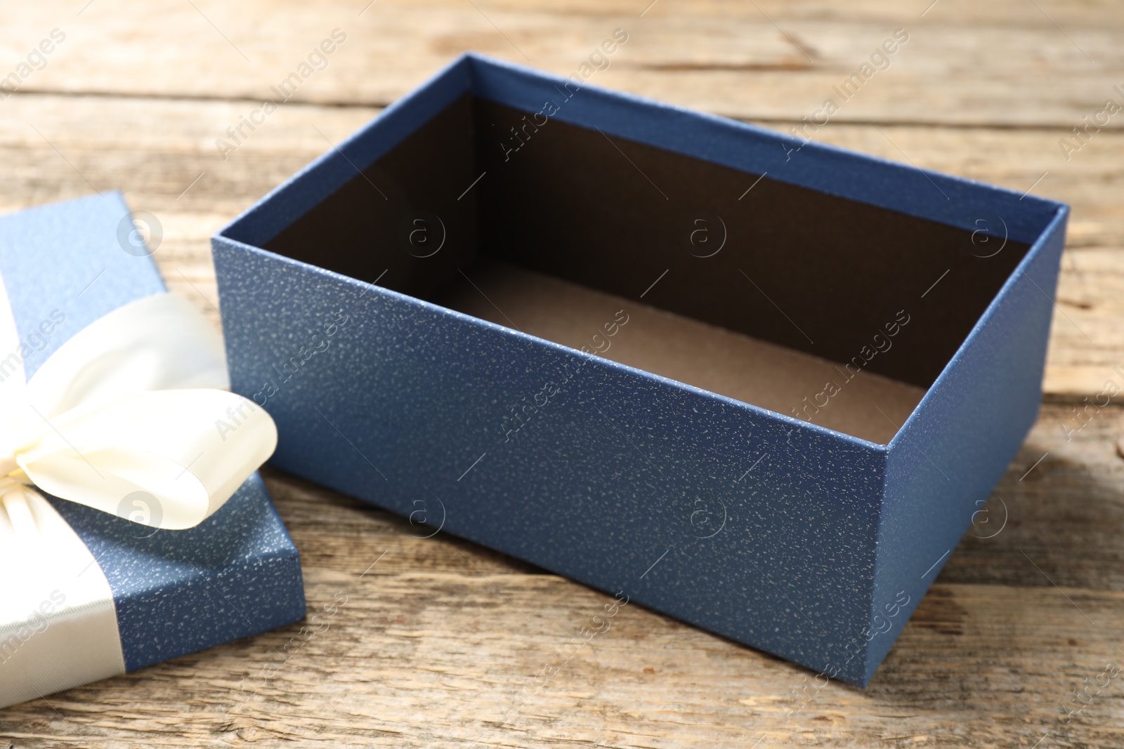 Photo of Opened gift box with beautiful lid on wooden table, closeup