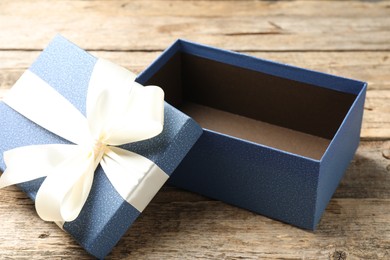 Photo of Opened gift box with beautiful lid on wooden table, closeup