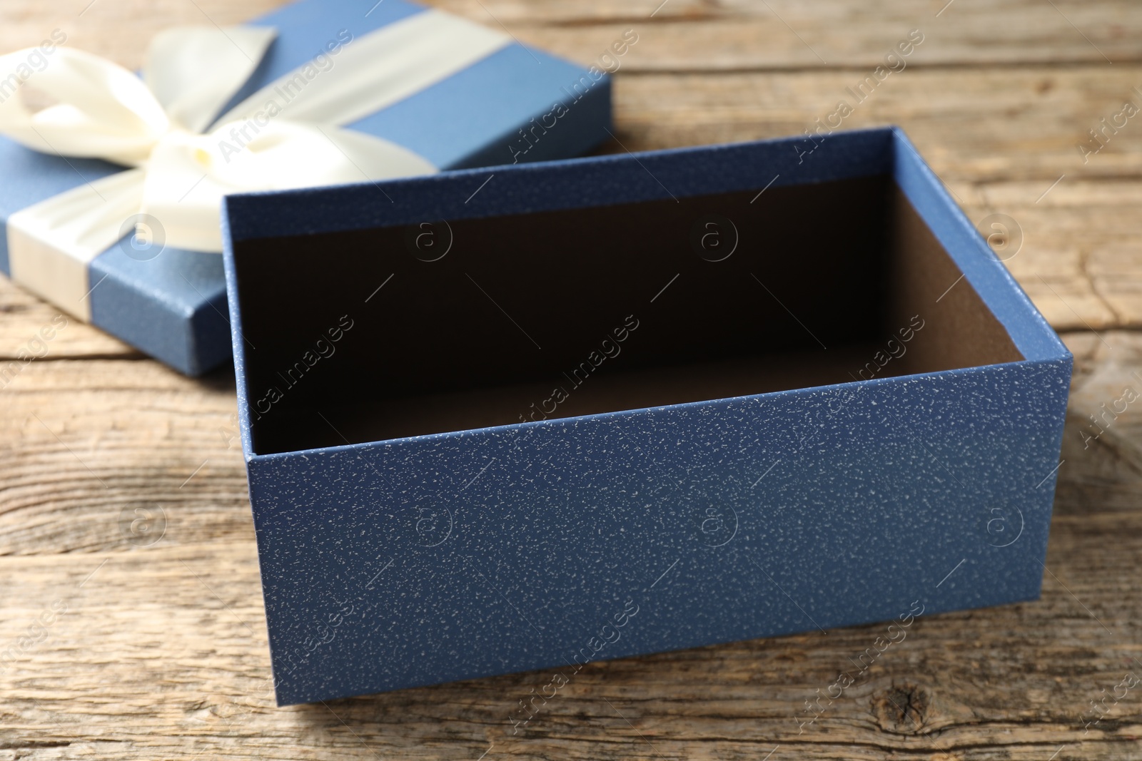 Photo of Opened gift box with beautiful lid on wooden table, closeup