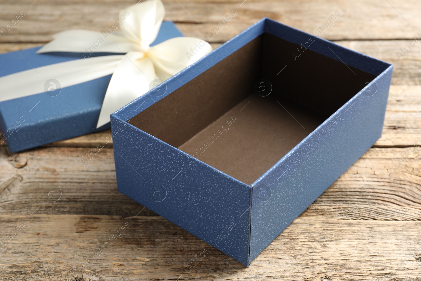 Photo of Opened gift box with beautiful lid on wooden table, closeup