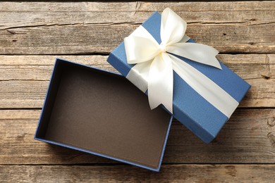 Photo of Opened gift box with beautiful lid on wooden table, top view