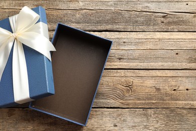 Photo of Opened gift box with beautiful lid on wooden table, top view. Space for text