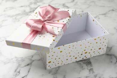 Photo of Opened gift box with beautiful lid on white marble table, closeup