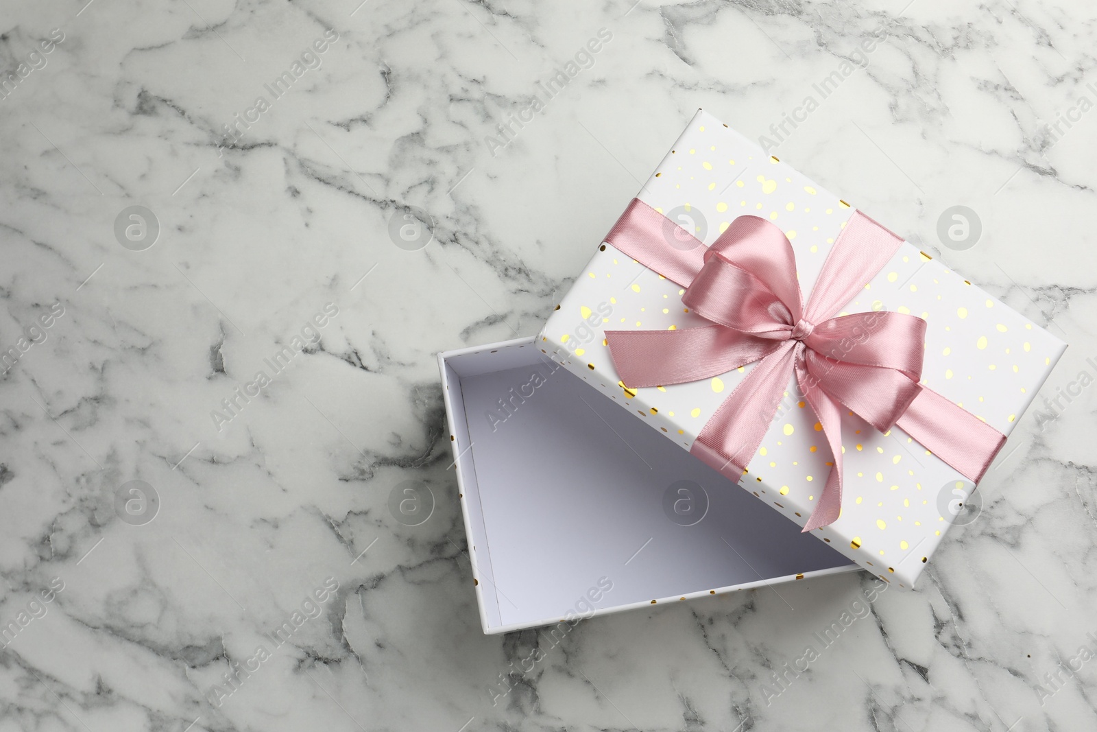 Photo of Opened gift box with beautiful lid on white marble table, top view. Space for text