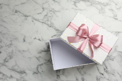 Photo of Opened gift box with beautiful lid on white marble table, top view. Space for text