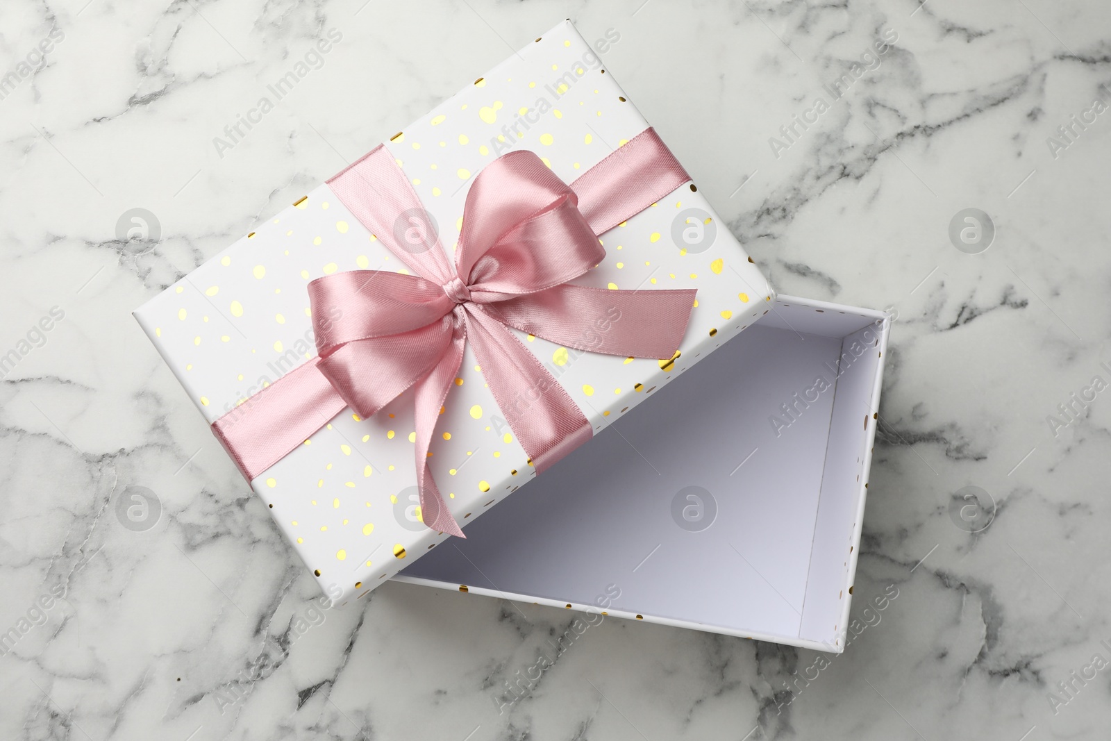 Opened gift box with beautiful lid on white marble table, top view Photo of Opened gift box with beautiful lid on white marble table, top view