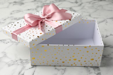 Photo of Opened gift box with beautiful lid on white marble table, closeup