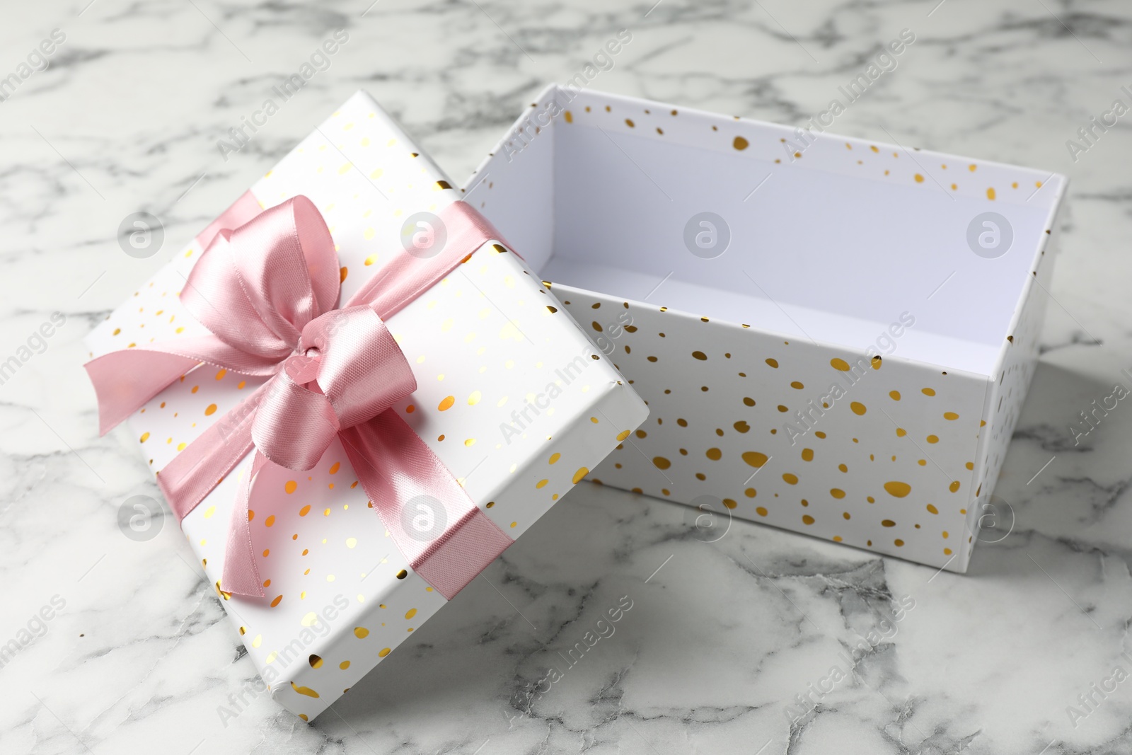 Photo of Opened gift box with beautiful lid on white marble table, closeup