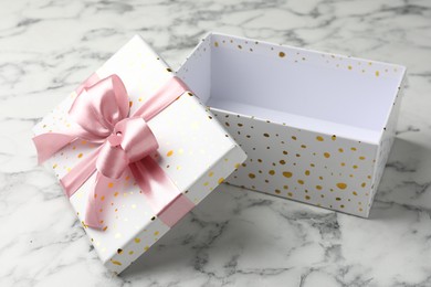 Photo of Opened gift box with beautiful lid on white marble table, closeup