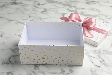 Photo of Opened gift box with beautiful lid on white marble table, closeup