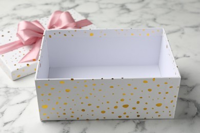 Photo of Opened gift box with beautiful lid on white marble table, closeup