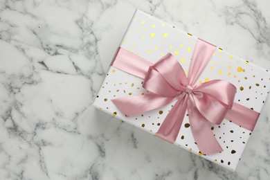 Photo of Gift box with beautiful bow on white marble table, top view. Space for text