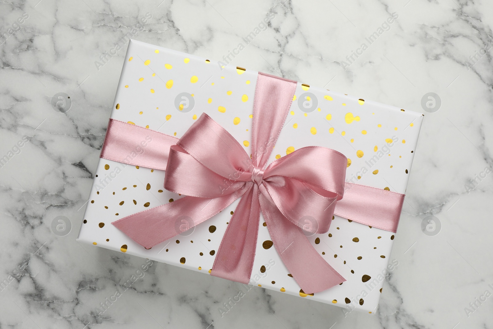 Photo of Gift box with beautiful bow on white marble table, top view