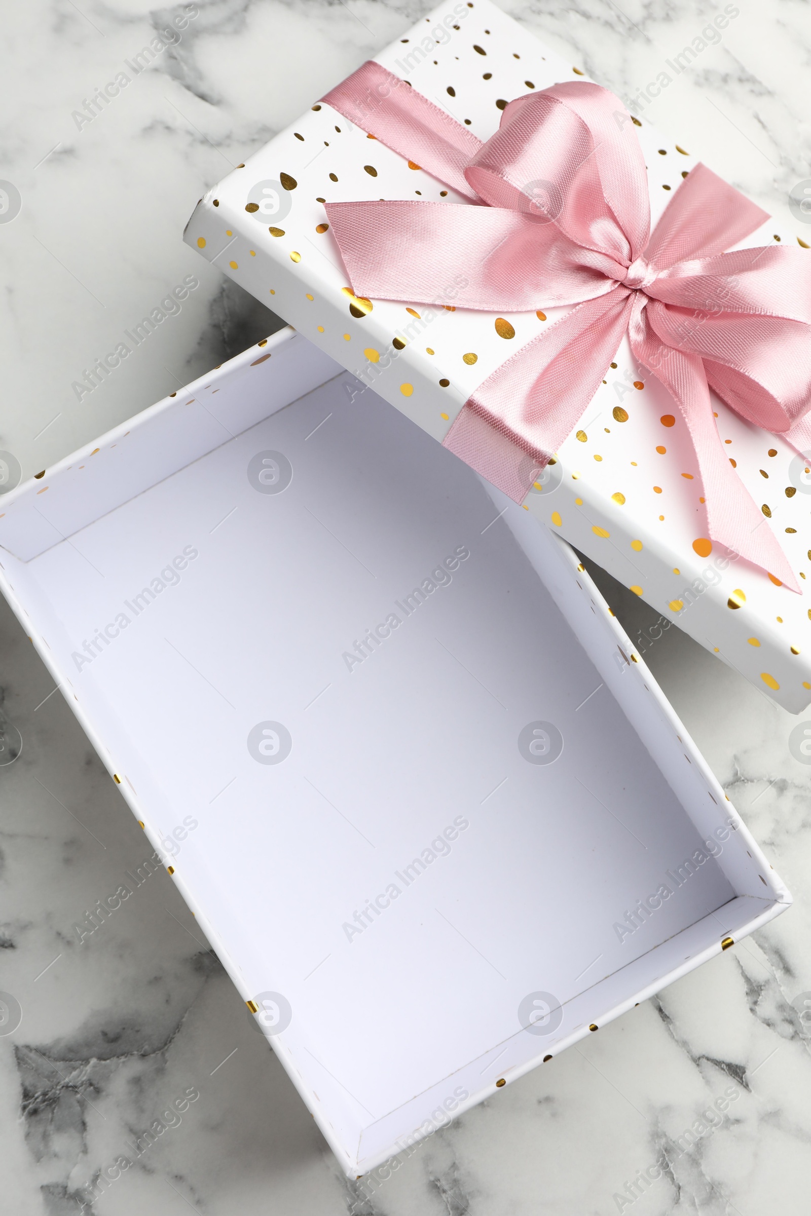 Photo of Opened gift box with beautiful lid on white marble table, top view