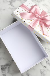 Photo of Opened gift box with beautiful lid on white marble table, top view