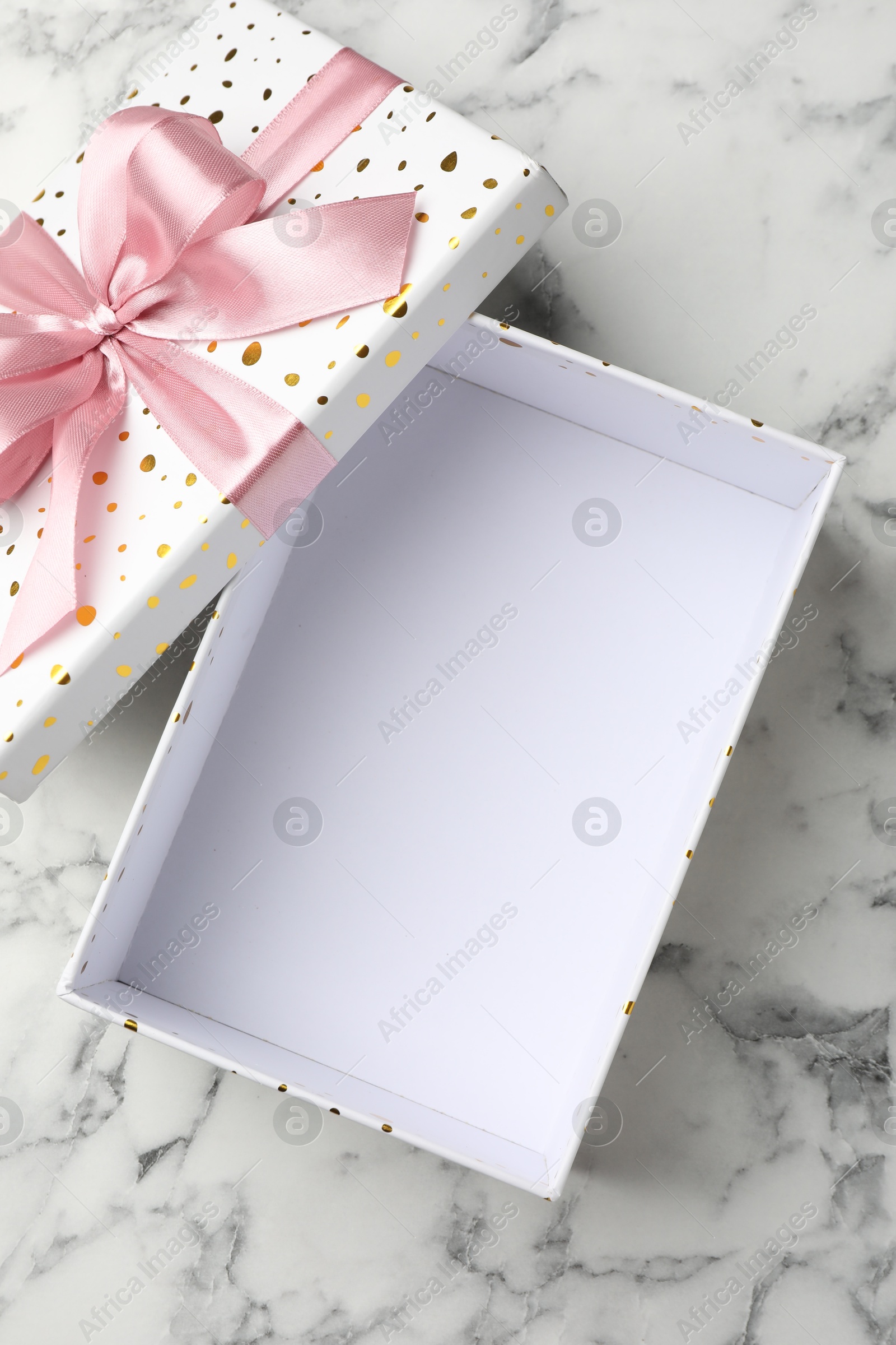 Photo of Opened gift box with beautiful lid on white marble table, top view