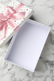 Photo of Opened gift box with beautiful lid on white marble table, top view