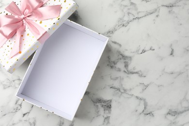 Photo of Opened gift box with beautiful lid on white marble table, top view. Space for text