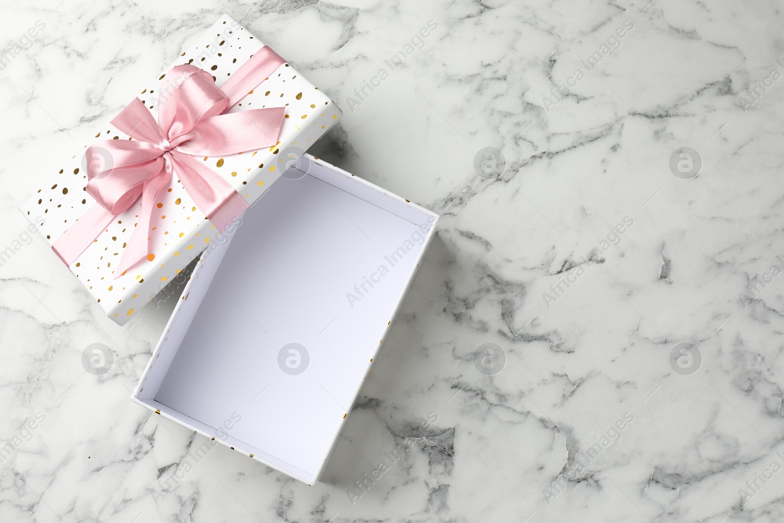 Photo of Opened gift box with beautiful lid on white marble table, top view. Space for text