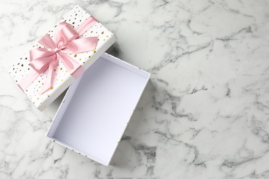 Photo of Opened gift box with beautiful lid on white marble table, top view. Space for text