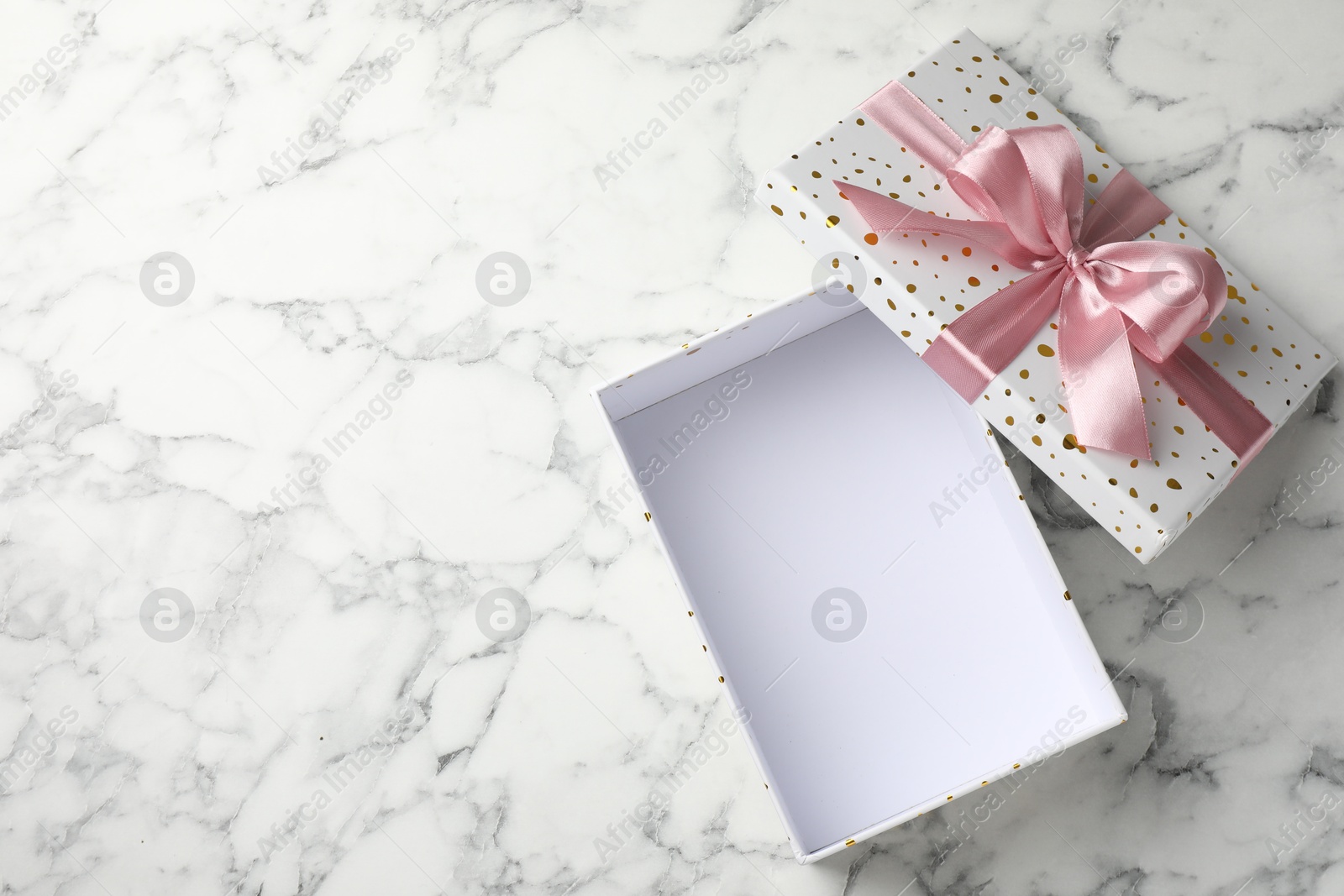 Photo of Opened gift box with beautiful lid on white marble table, top view. Space for text