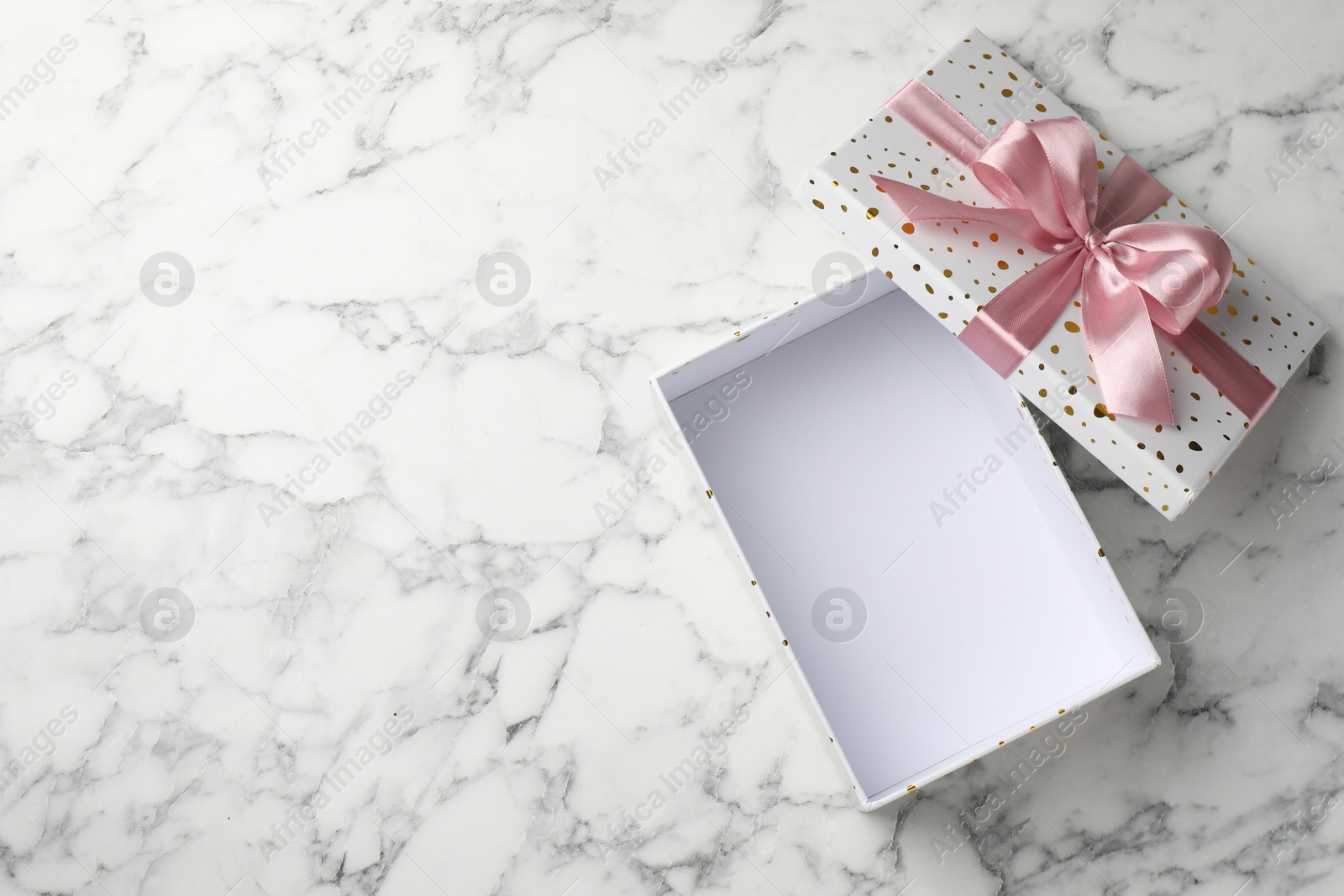 Photo of Opened gift box with beautiful lid on white marble table, top view. Space for text