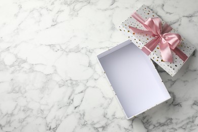 Photo of Opened gift box with beautiful lid on white marble table, top view. Space for text