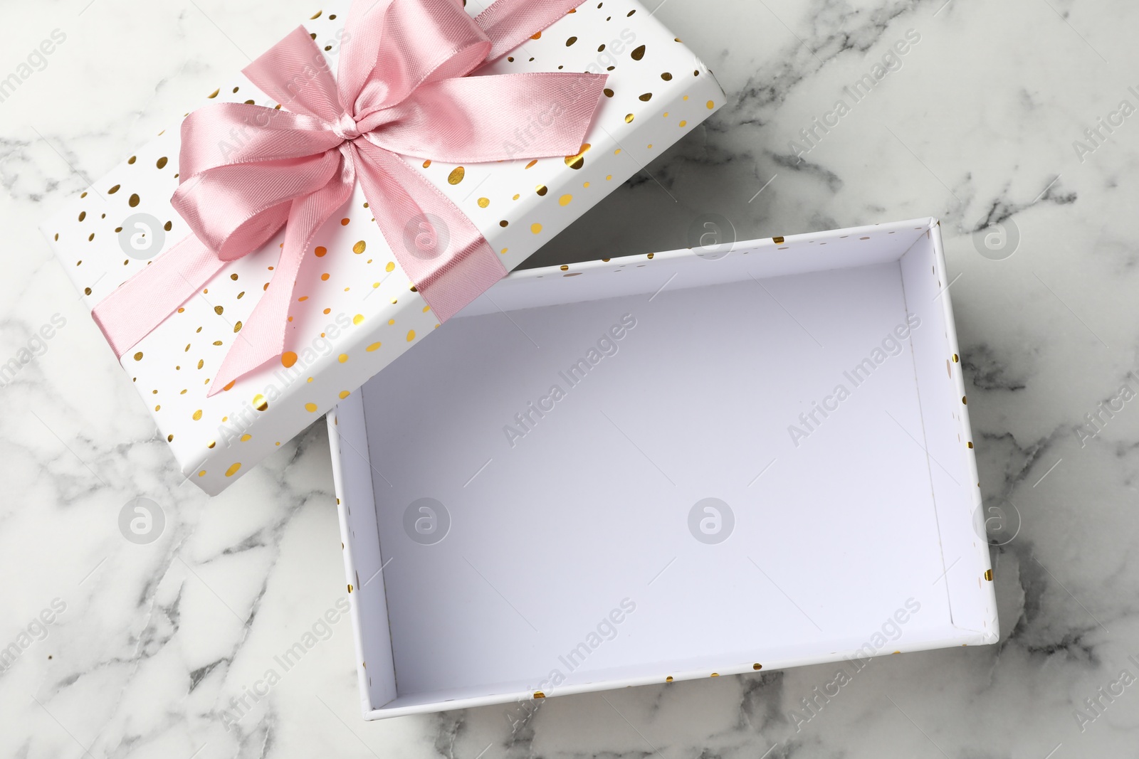 Photo of Opened gift box with beautiful lid on white marble table, top view