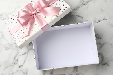 Photo of Opened gift box with beautiful lid on white marble table, top view