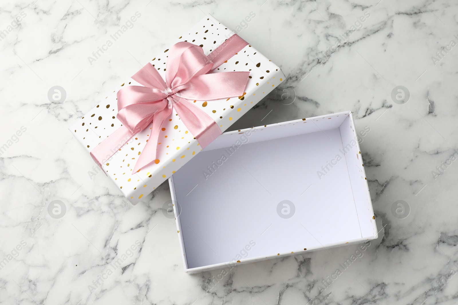Photo of Opened gift box with beautiful lid on white marble table, top view