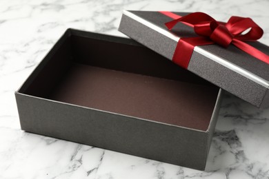 Photo of Opened gift box with beautiful lid on white marble table, closeup