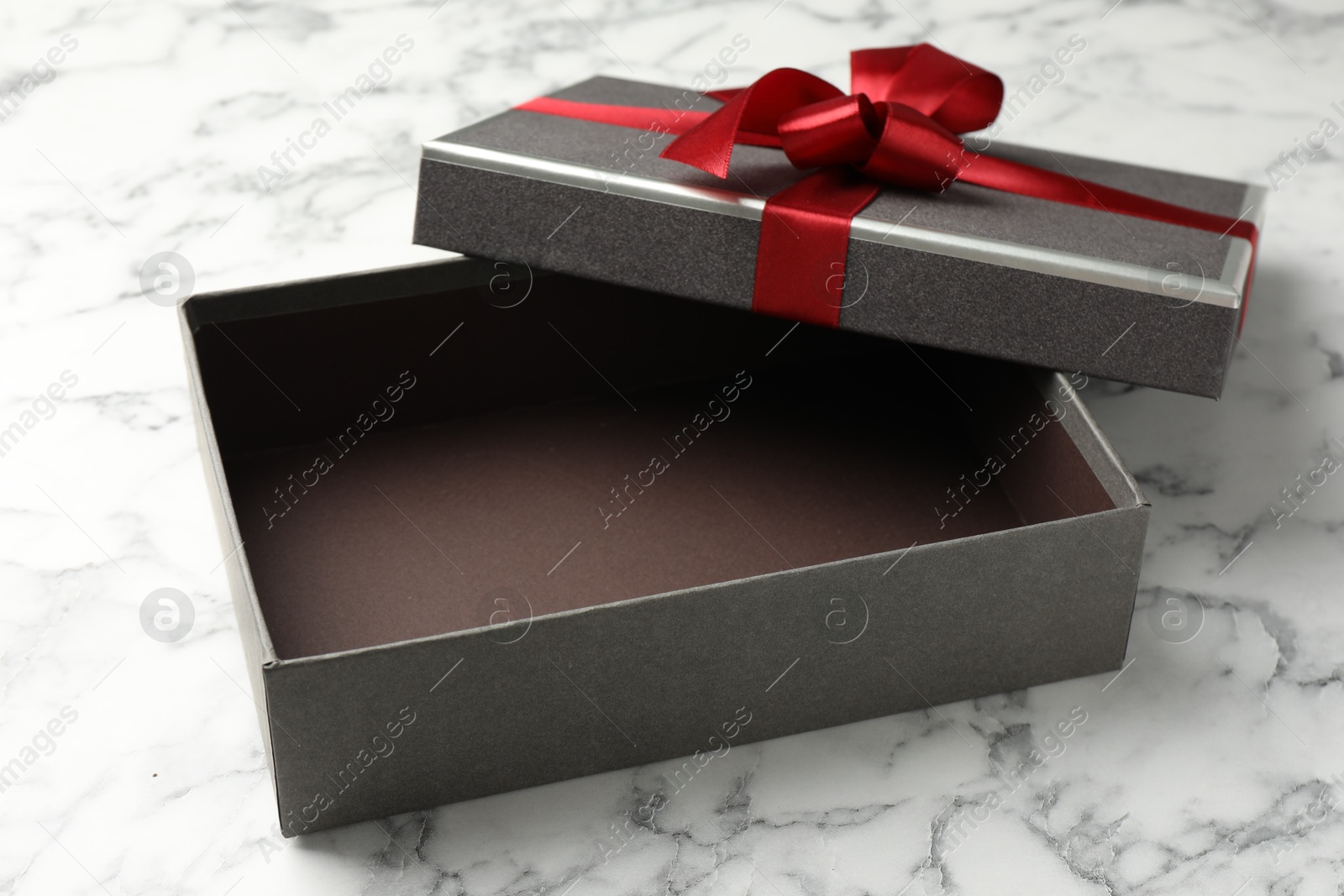 Photo of Opened gift box with beautiful lid on white marble table, closeup