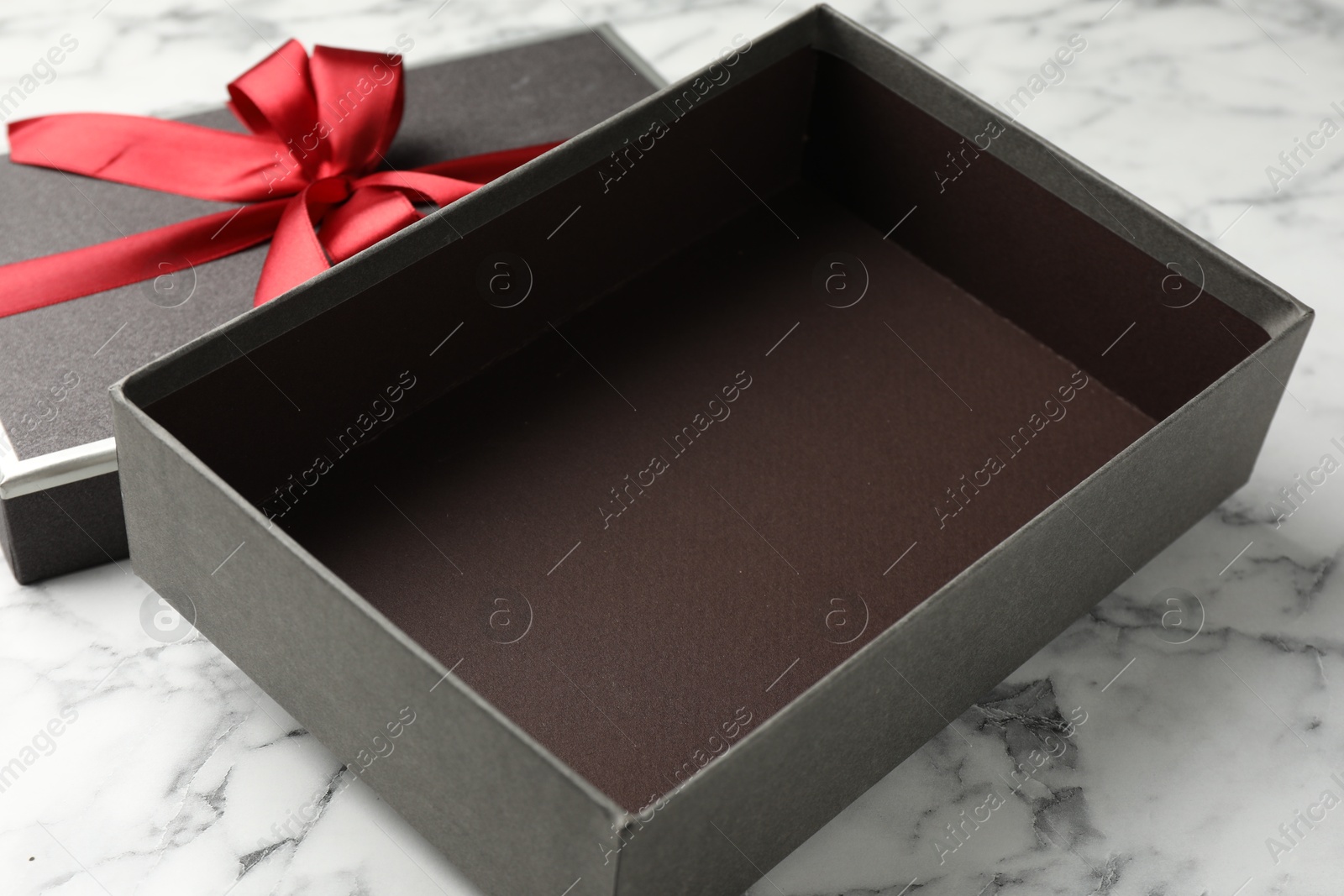Photo of Opened gift box with beautiful lid on white marble table, closeup