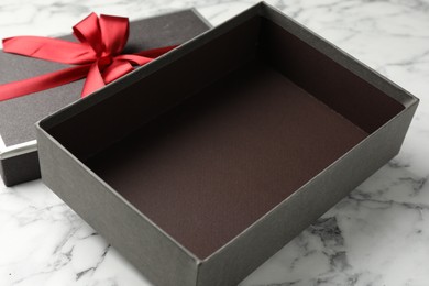 Photo of Opened gift box with beautiful lid on white marble table, closeup