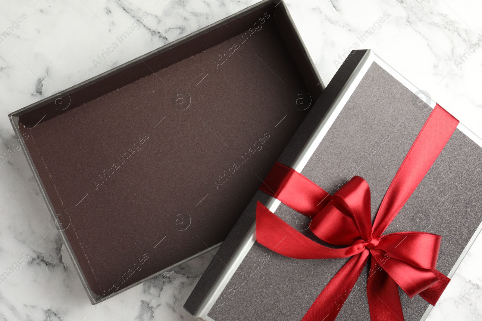 Photo of Opened gift box with beautiful lid on white marble table, top view