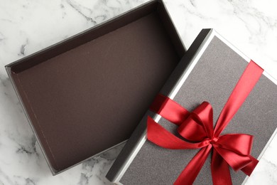 Photo of Opened gift box with beautiful lid on white marble table, top view
