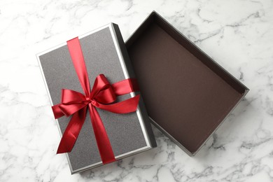 Photo of Opened gift box with beautiful lid on white marble table, top view