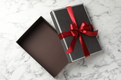 Photo of Opened gift box with beautiful lid on white marble table, top view