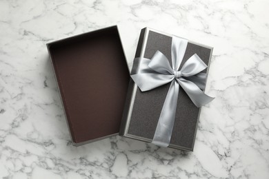 Photo of Opened gift box with beautiful lid on white marble table, top view