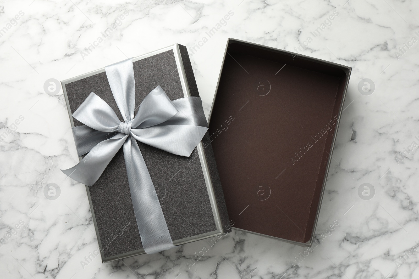 Photo of Opened gift box with beautiful lid on white marble table, top view