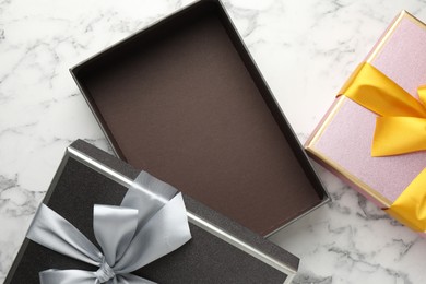 Photo of Opened and closed gift boxes with beautiful bows on white marble table, top view