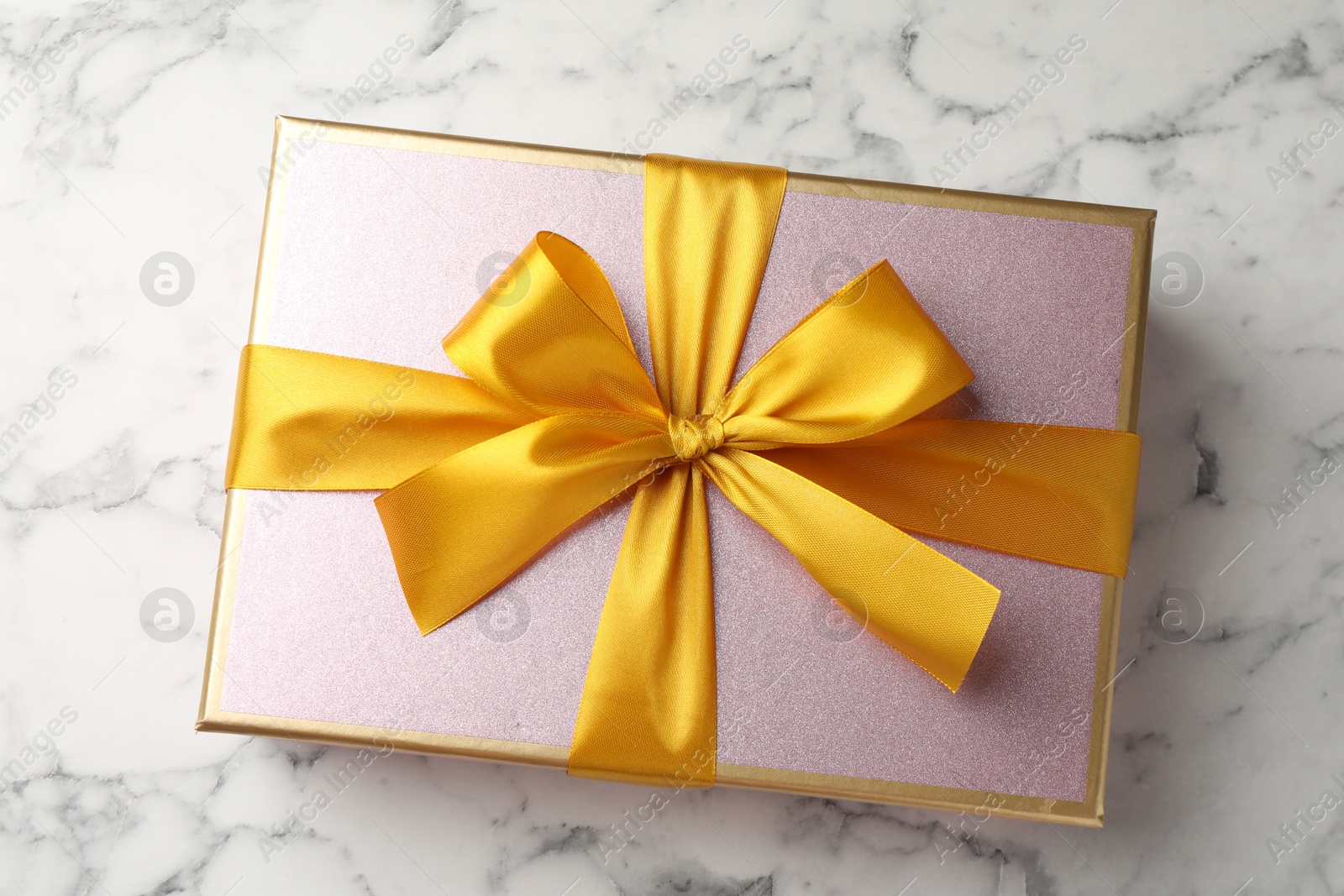 Photo of Gift box with beautiful bow on white marble table, top view