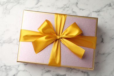 Photo of Gift box with beautiful bow on white marble table, top view