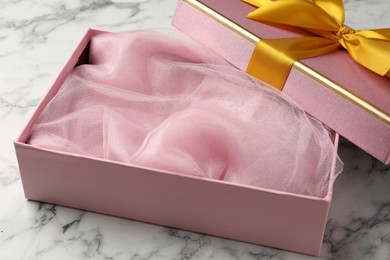 Photo of Opened gift box with beautiful lid on white marble table, closeup